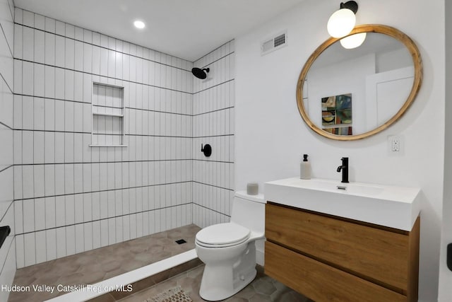 bathroom featuring tiled shower, tile patterned floors, vanity, and toilet