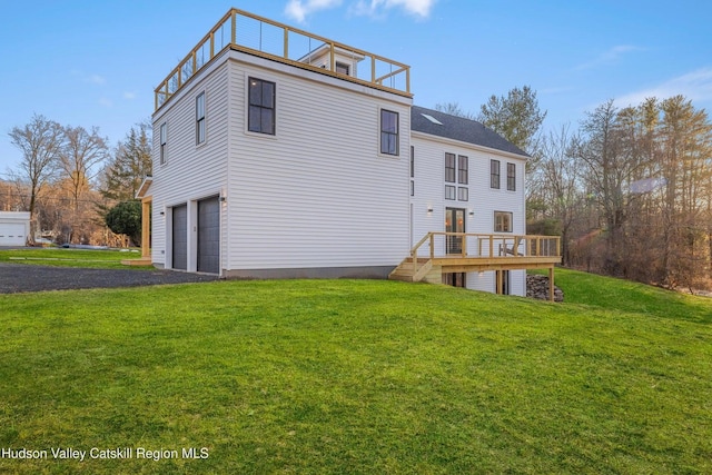 back of house with a garage, a yard, and a balcony