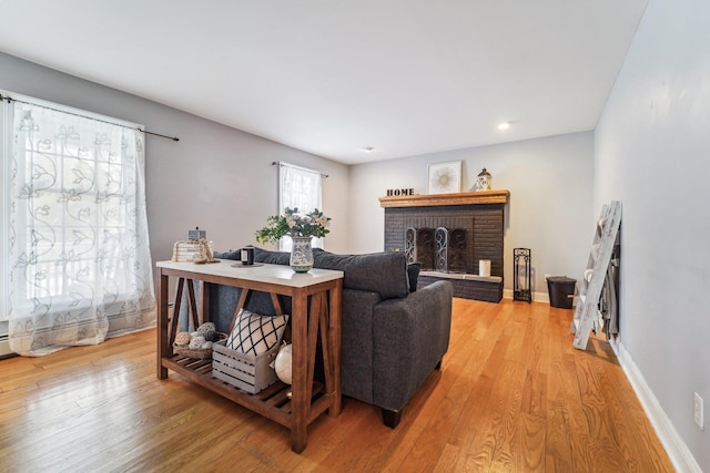 living room with a brick fireplace and light hardwood / wood-style flooring