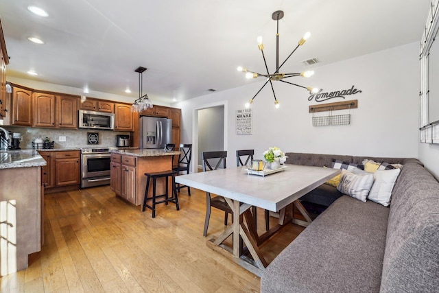 kitchen featuring pendant lighting, stainless steel appliances, a kitchen breakfast bar, a kitchen island, and breakfast area