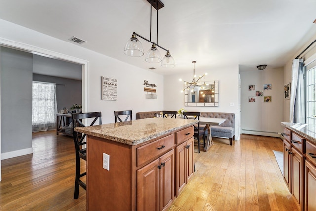 kitchen featuring a center island, pendant lighting, a kitchen bar, and light hardwood / wood-style flooring