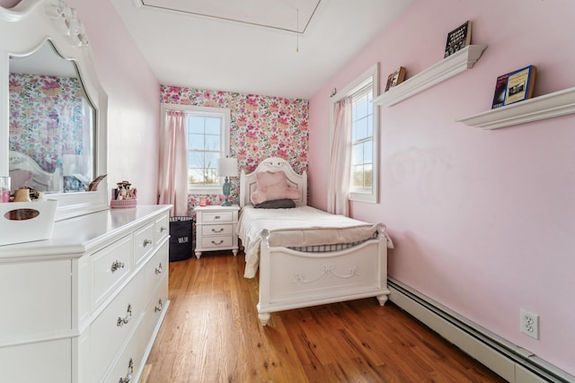 bedroom with hardwood / wood-style flooring, multiple windows, and a baseboard heating unit