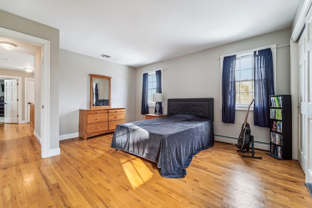 bedroom with a baseboard radiator and light hardwood / wood-style floors