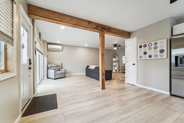 interior space featuring beamed ceiling, a wall mounted AC, and light hardwood / wood-style floors