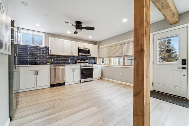 kitchen with white cabinetry, stainless steel appliances, decorative backsplash, and a wealth of natural light