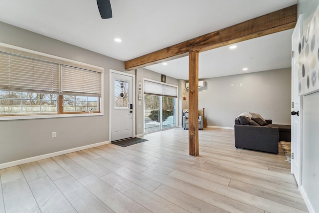 entrance foyer with ceiling fan, an AC wall unit, beam ceiling, and light hardwood / wood-style floors