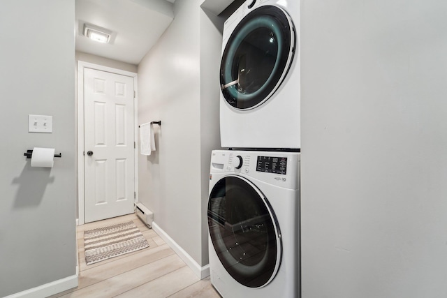 clothes washing area with a baseboard radiator, light hardwood / wood-style floors, and stacked washer and clothes dryer