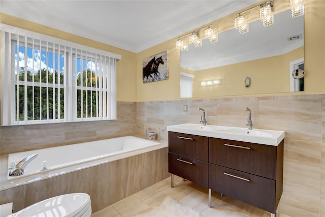 bathroom with tile patterned floors, tiled tub, toilet, vanity, and tile walls