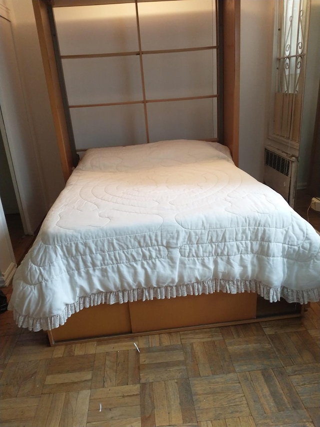 bedroom with dark parquet flooring and radiator heating unit