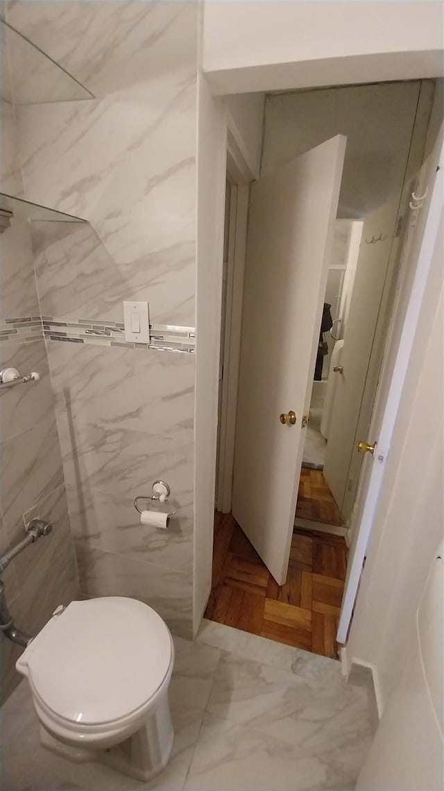 bathroom featuring tile walls and toilet