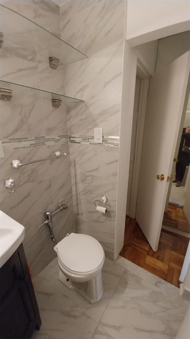 bathroom with vanity, toilet, and tile walls