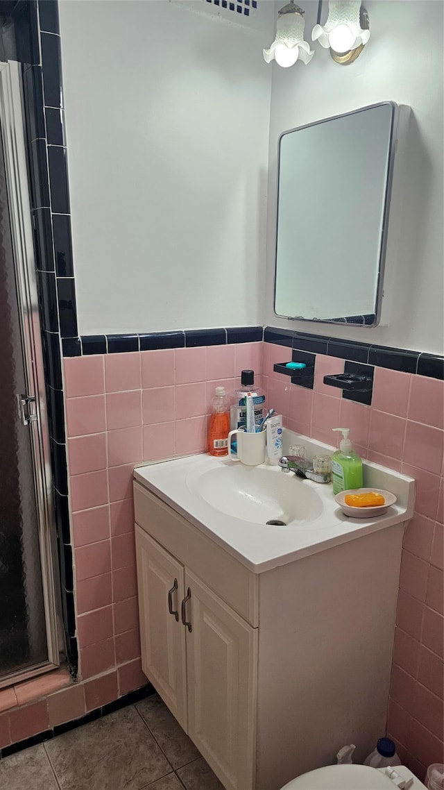 bathroom featuring tile patterned floors, a shower with door, vanity, and tile walls