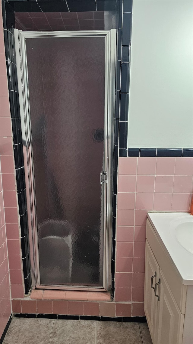 bathroom with tile patterned flooring, vanity, tile walls, and an enclosed shower