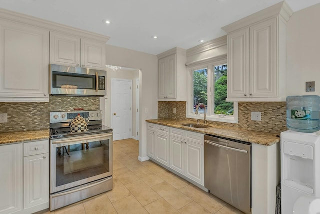 kitchen with tasteful backsplash, white cabinetry, sink, and stainless steel appliances