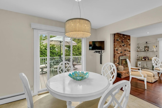 dining area featuring a fireplace, light wood-type flooring, and baseboard heating