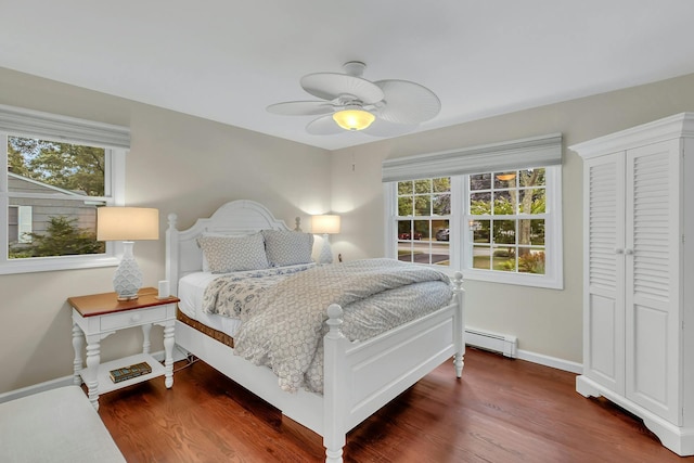 bedroom featuring multiple windows, dark hardwood / wood-style flooring, a baseboard radiator, and ceiling fan