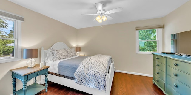 bedroom featuring dark hardwood / wood-style floors, ceiling fan, and multiple windows