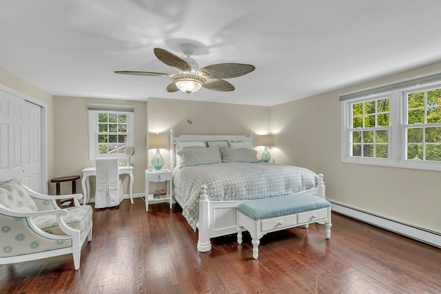 bedroom featuring ceiling fan, dark wood-type flooring, a baseboard radiator, and a closet