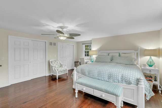 bedroom with two closets, ceiling fan, and dark hardwood / wood-style floors