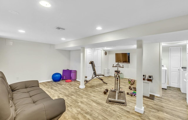 exercise area with light wood-type flooring and separate washer and dryer