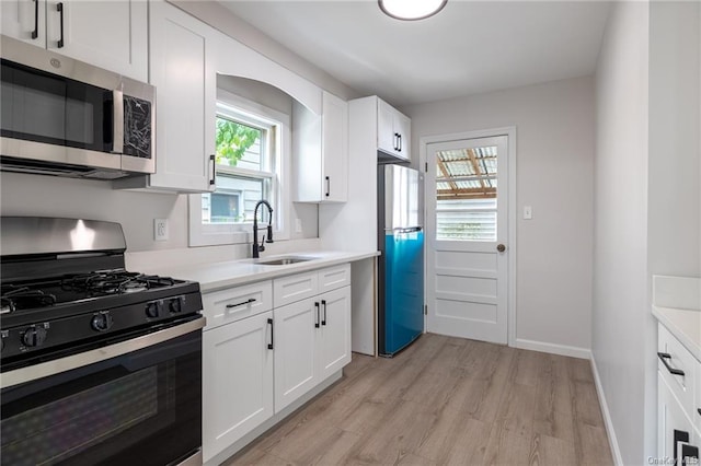 kitchen featuring white cabinets, appliances with stainless steel finishes, light wood-type flooring, and sink