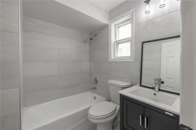 full bathroom featuring toilet, vanity, tile walls, and tiled shower / bath