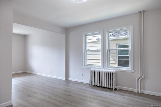 empty room featuring radiator and light hardwood / wood-style flooring