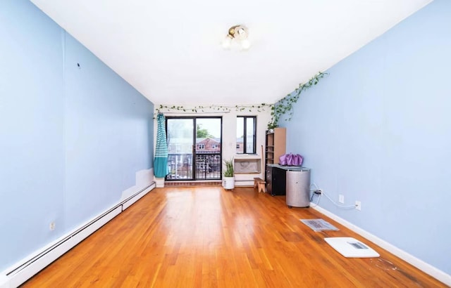 empty room featuring wood-type flooring and a baseboard heating unit