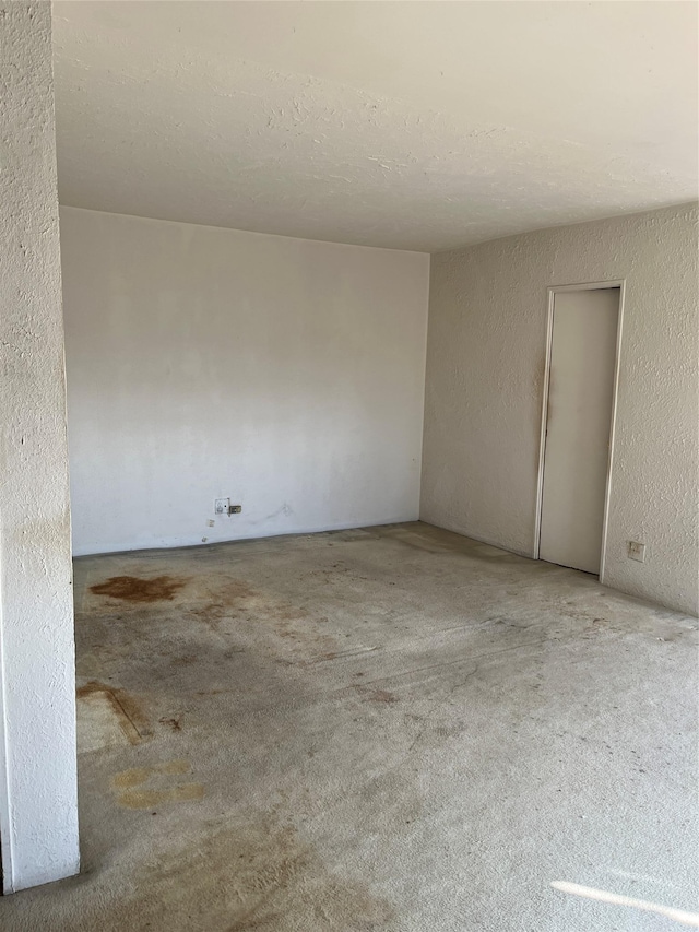 carpeted spare room with a textured ceiling