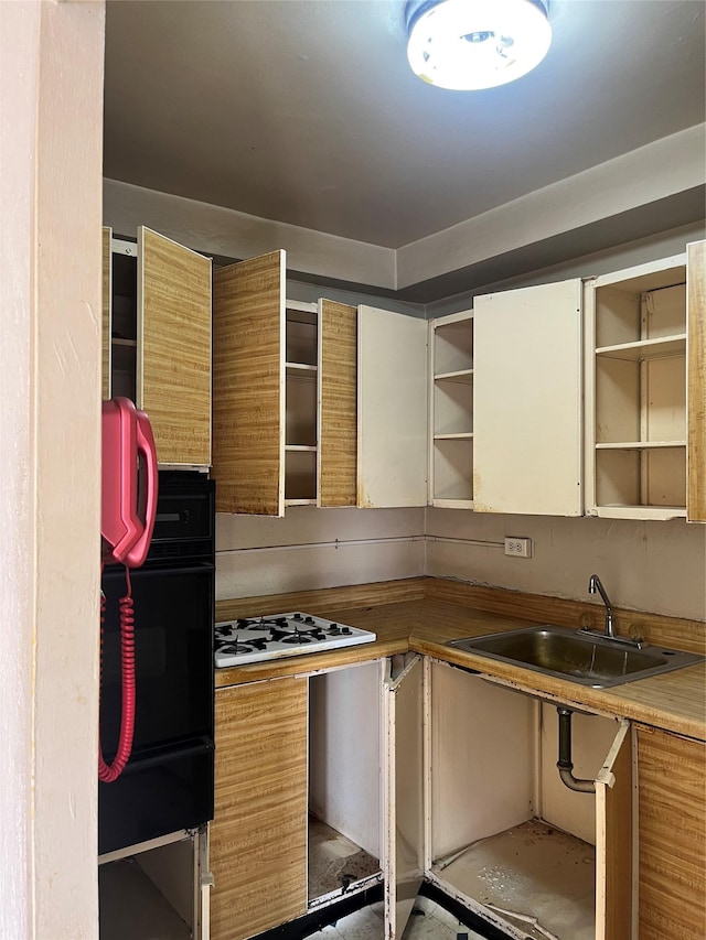 kitchen with black oven, white gas stovetop, and sink