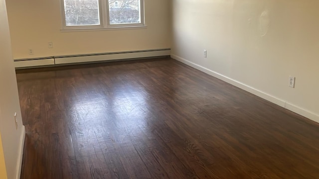 unfurnished room featuring a baseboard heating unit and dark wood-type flooring