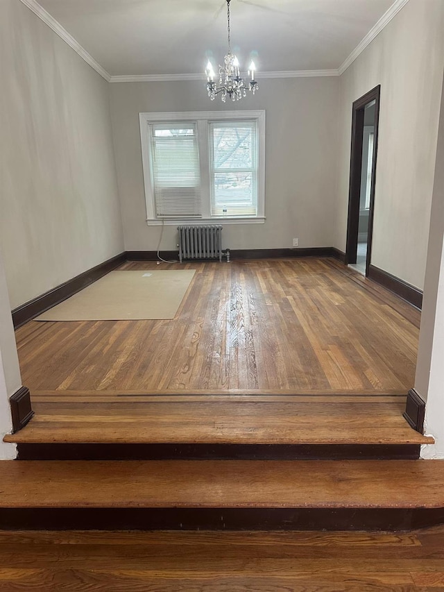 unfurnished dining area featuring hardwood / wood-style floors, ornamental molding, radiator, and a chandelier