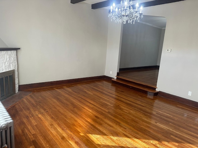 interior space with a stone fireplace, ornamental molding, dark wood-type flooring, and an inviting chandelier