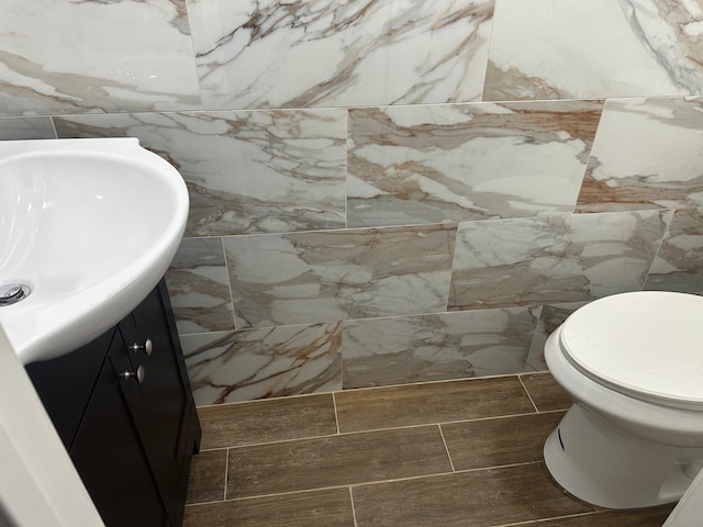 bathroom featuring vanity, toilet, and tile walls