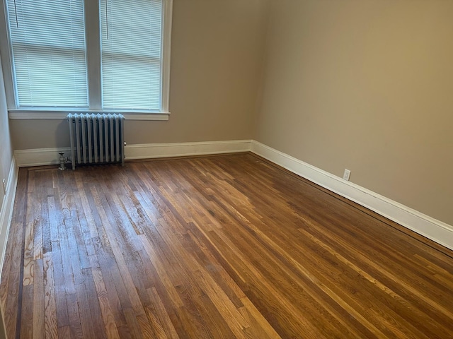 spare room featuring dark hardwood / wood-style floors and radiator