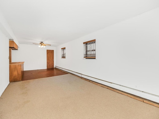 carpeted spare room featuring ceiling fan and a baseboard heating unit