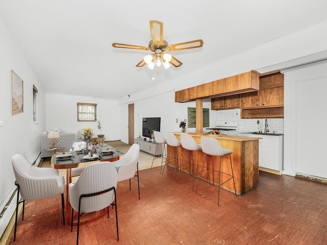 dining room featuring ceiling fan, sink, and baseboard heating