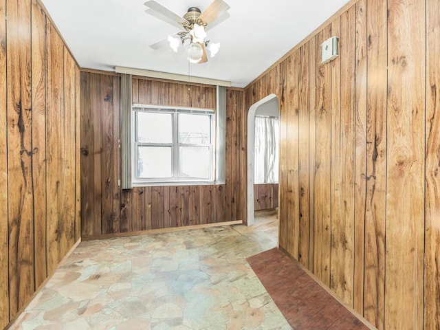 spare room featuring ceiling fan and wood walls