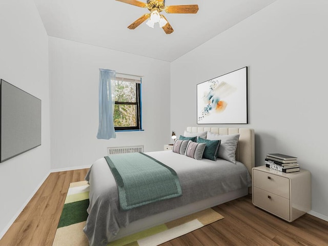 bedroom featuring wood-type flooring, radiator heating unit, and ceiling fan