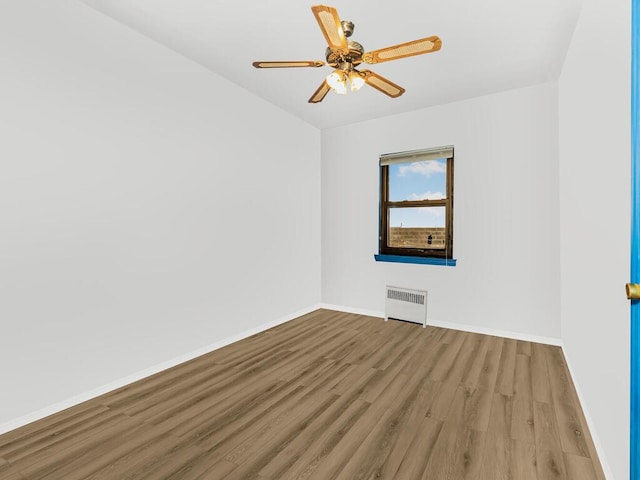 spare room with ceiling fan, radiator heating unit, and hardwood / wood-style flooring