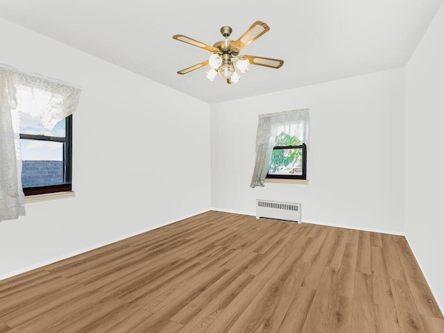 spare room featuring ceiling fan, light hardwood / wood-style floors, and radiator