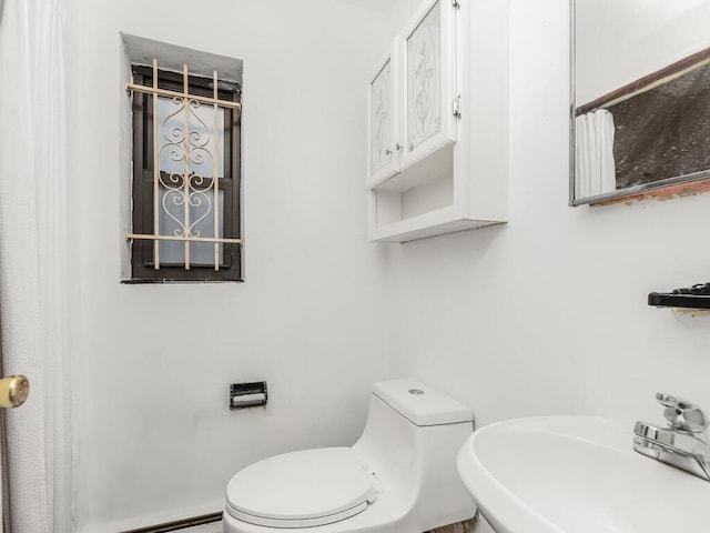 bathroom with toilet, a baseboard heating unit, and sink