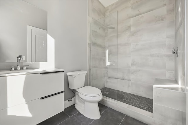 bathroom with toilet, vanity, a tile shower, and tile patterned flooring