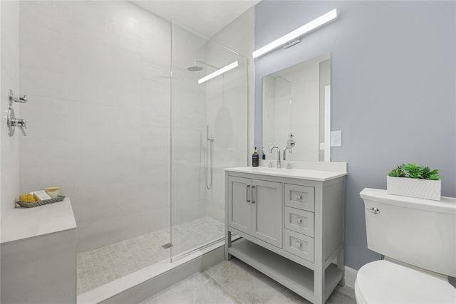 bathroom with tiled shower, vanity, and toilet