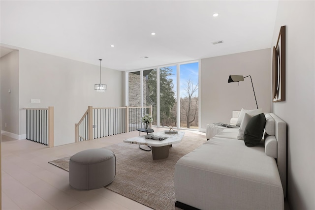 living room featuring light wood-type flooring, a wall of windows, and a notable chandelier