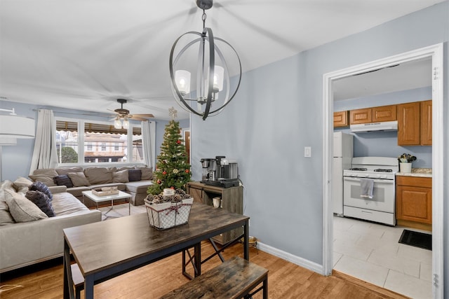 dining room featuring ceiling fan with notable chandelier and light hardwood / wood-style floors