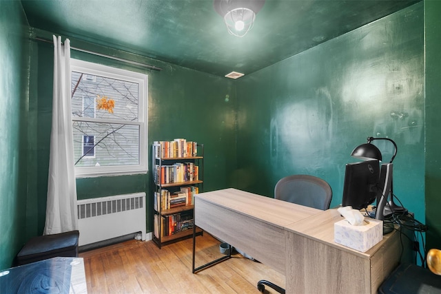 office with radiator heating unit and hardwood / wood-style floors