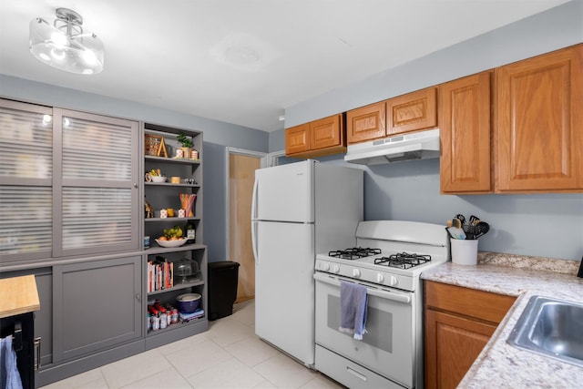 kitchen featuring white appliances, sink, and light tile patterned floors