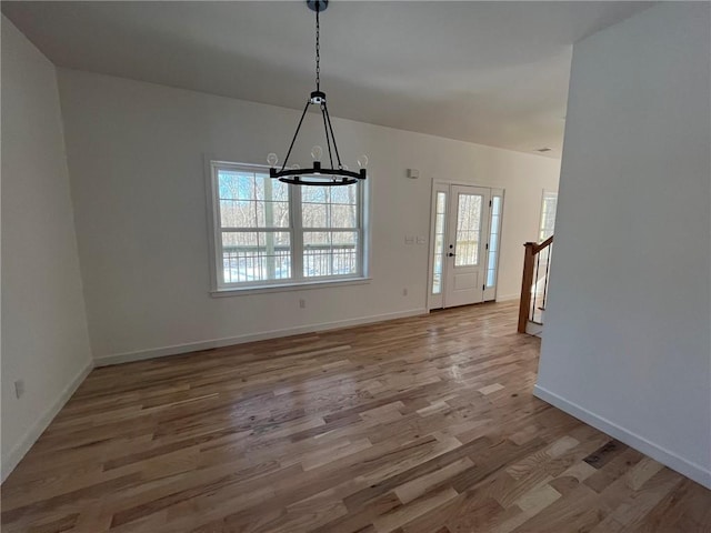 unfurnished dining area featuring a notable chandelier, plenty of natural light, and wood-type flooring