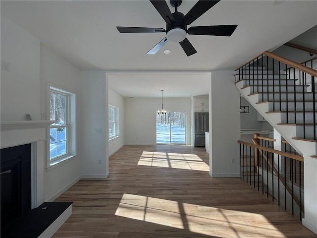 unfurnished living room featuring dark hardwood / wood-style flooring, plenty of natural light, and ceiling fan with notable chandelier